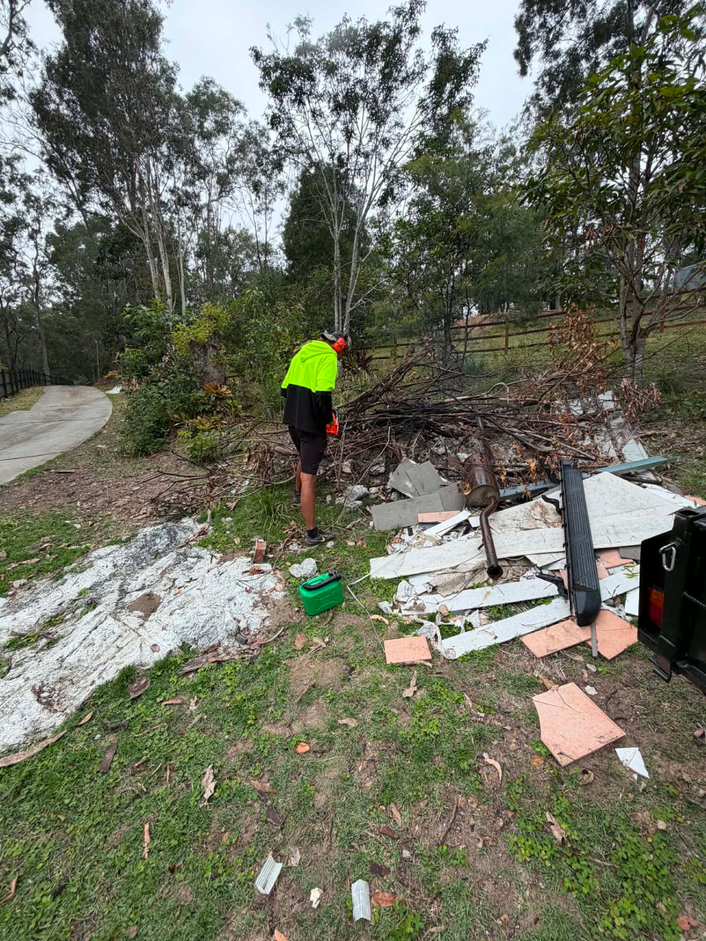 Worker cutting up branches and loading green waste and rubbish